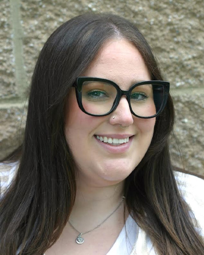 A woman wearing glasses and smiling at the camera.